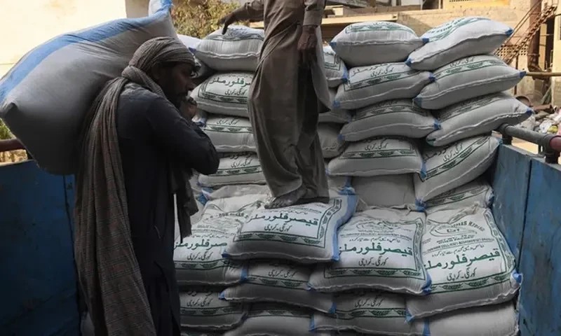 Workers loading sacks of wheat flour onto a truck at a grain market
