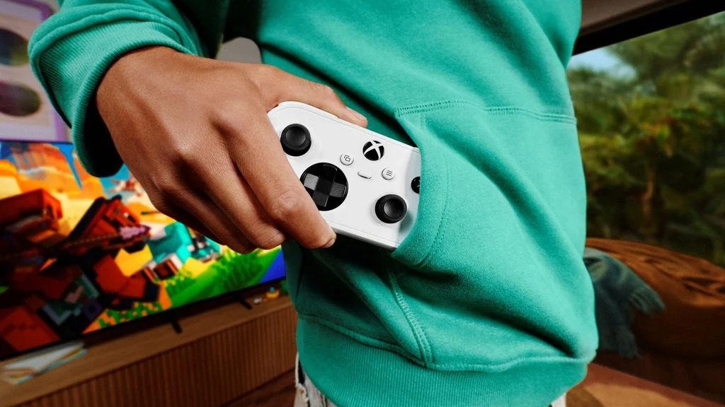 The white Xbox Nano Controller slipping into a hoodie pocket, showing its portable size