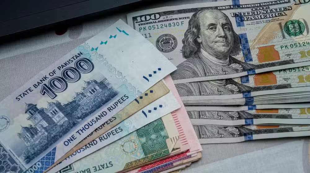 Pakistani rupee banknotes next to US dollar bills